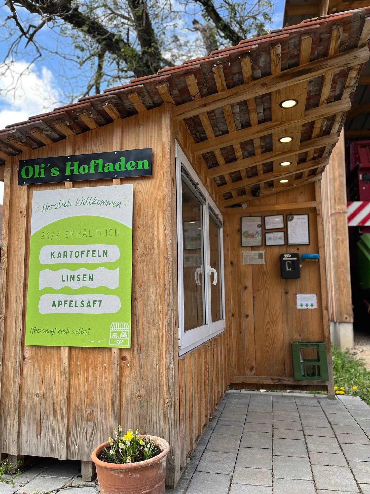 Olis Hofladen: Holzhütte mit grünem Schild, 24/7 erhältlich: Kartoffeln, Linsen, Apfelsaft
